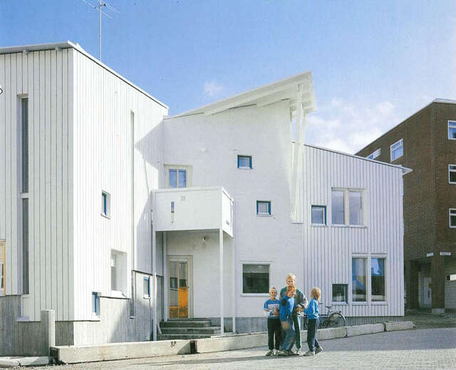 Wooden white painted daycare centre and a square in front of it