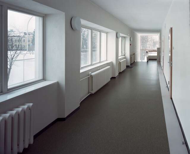 Hallway with a grey laminate floor and white walls, the windows show a snowy landscape.