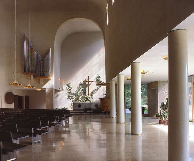View from the nave to the altar. Bench rows at the left, windows at the right.