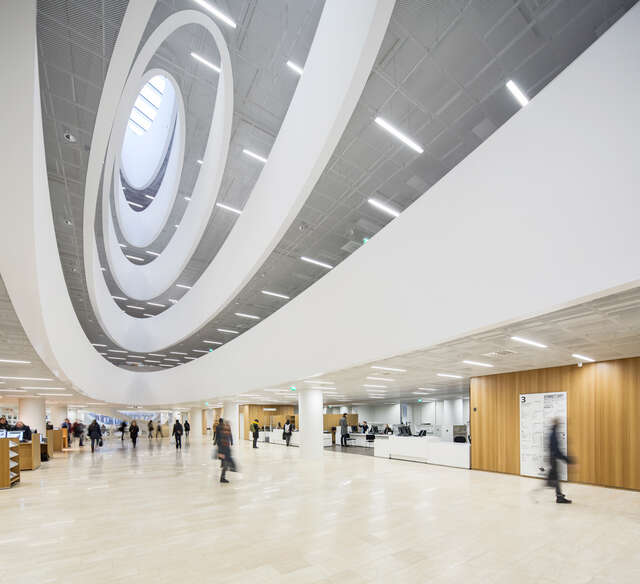 Lobby view to the library shelves, stairs and service desk, and to the rising oval-shaped upper floors and the oculus