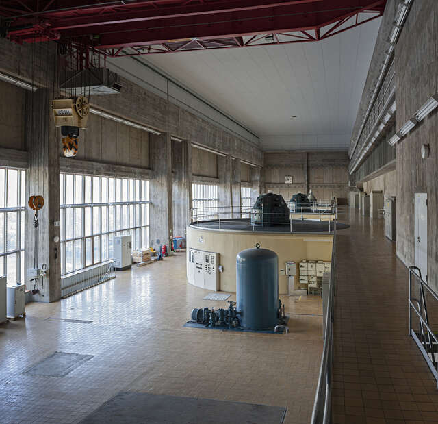 Interior view of the machine hall with round, yellow machinery and lots of natural light from rectangular windows.