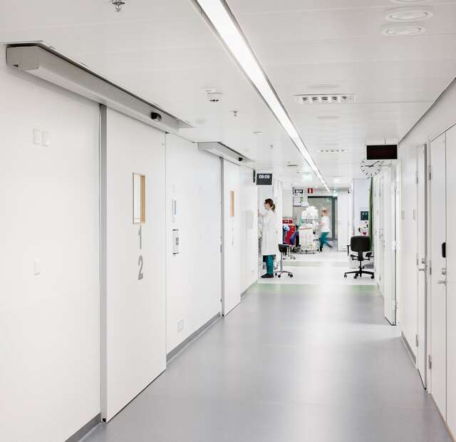 White hospital corridor with a doctor and nurse working.