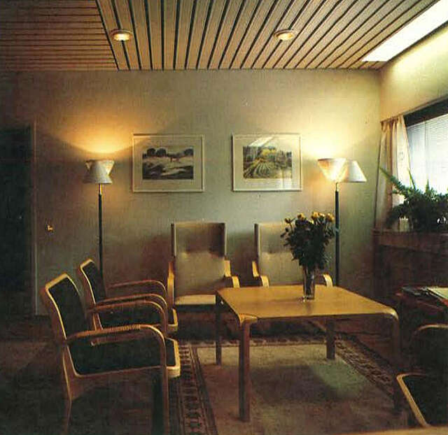 Interior with several chairs, table, lamps and artwork.