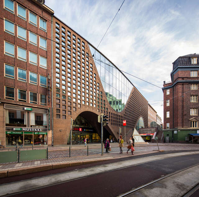 Red brick façade, small square shaped windows and a semiarch glass wall entrance