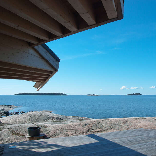 Wooden canopy and terrace next to rock and sea view