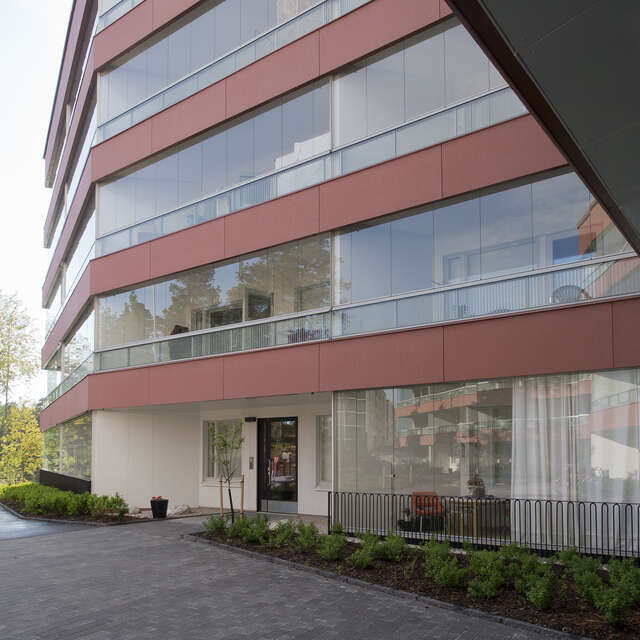 Close up shot of a Four storey apartment building with red metal panels on each floor.