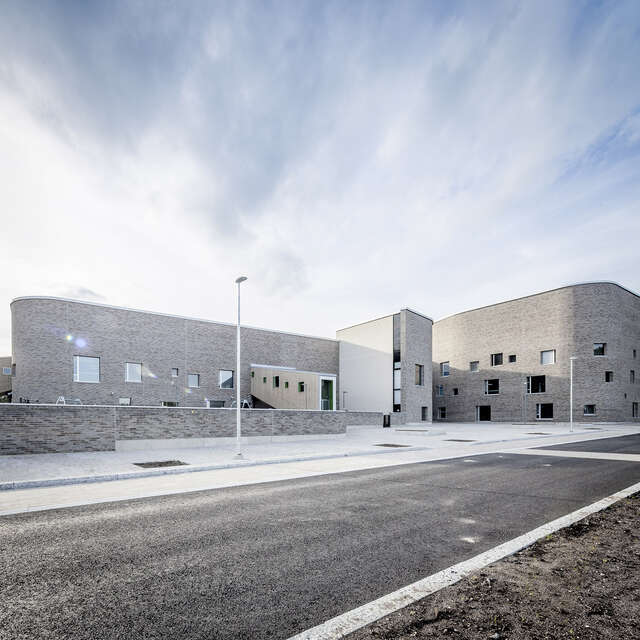 Grey-brick building with a modern feel on a sunny day.