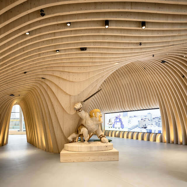 Wooden curvy structure interior with statue in the foreground.