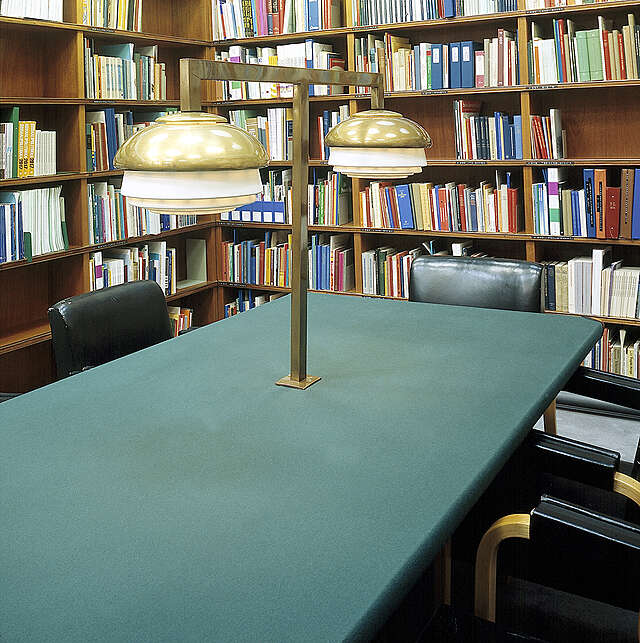 Green table wit leather covered chairs in a library corner.