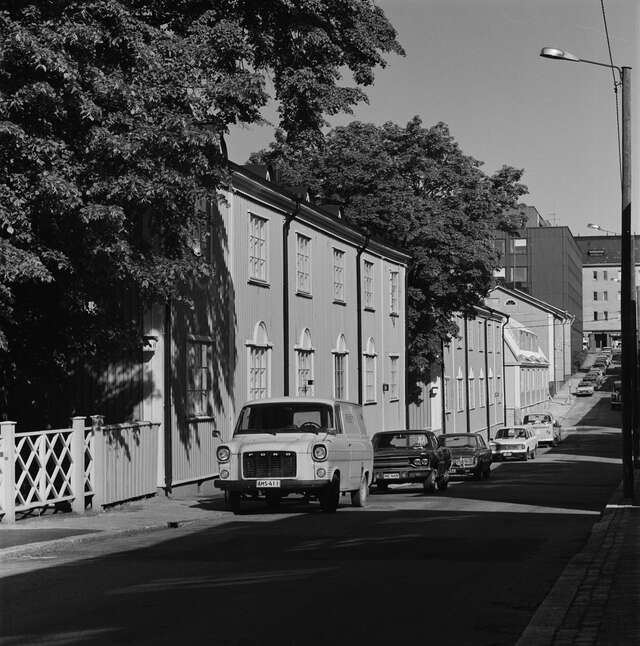 Row of wooden houses on a sloped street in a black and white picture.