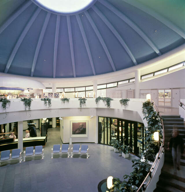 Hall with a cupola shaped ceiling, in the middle there is a ceiling window.The white surfaces and house plants give the room a fresh feeling.