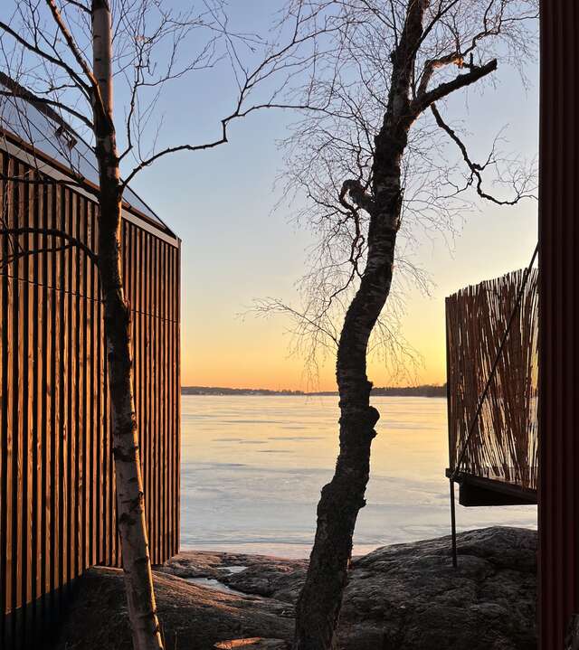 Sunset view from between two wooden cabins towards frozen sea
