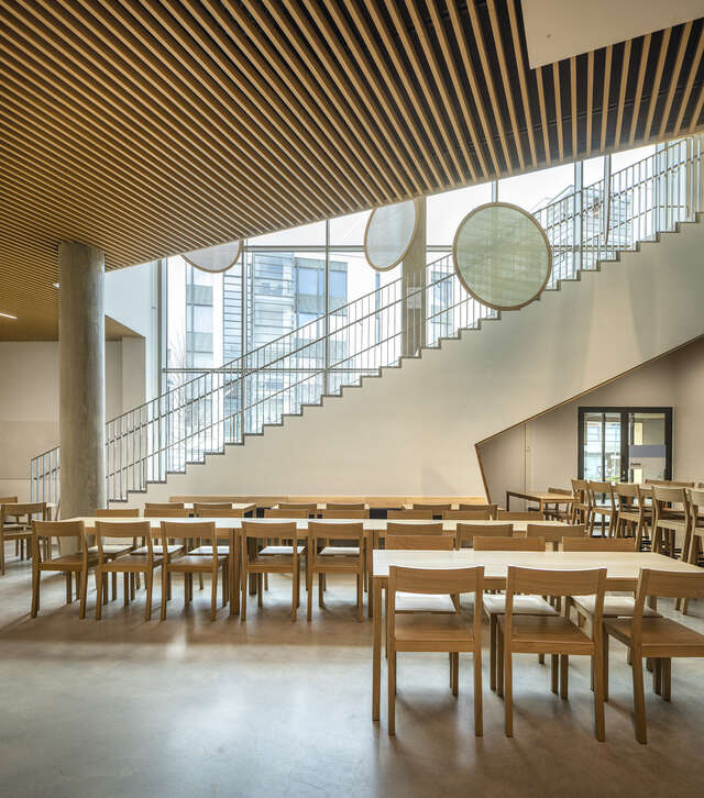 A large staircase with several tables and chairs nearby with round ornaments hanging from the ceiling
