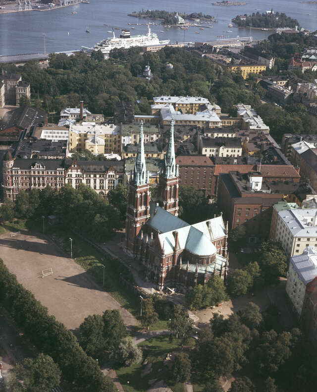 Aerial view of the Gothic-style stone church located in the middle of green parks and apartment houses