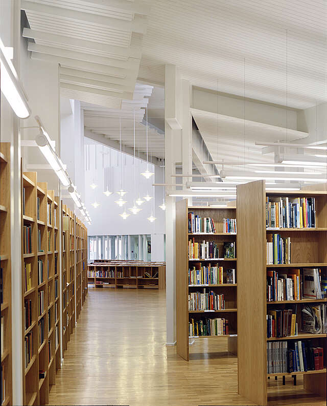 Light library interior with wooden bookshelves and pendant lights.