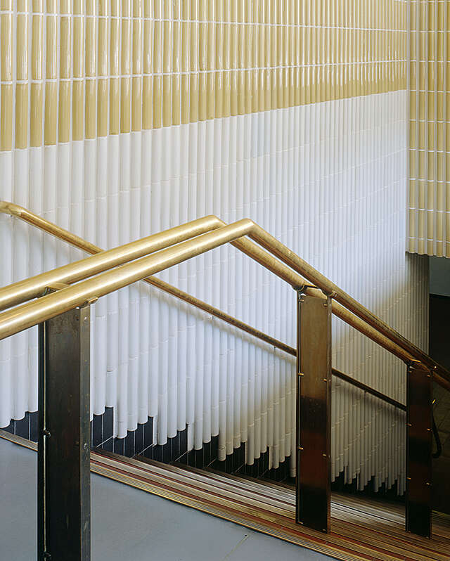 Gold colored railing in a white and beige stairway.