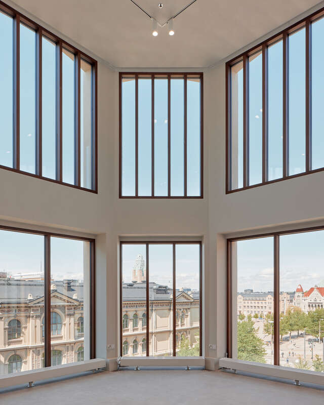 Large windows in two stories looking out at city rooftops.