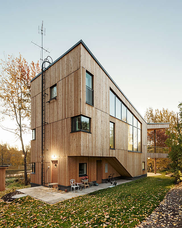 Wooden house with a sharp corner, multiple windows and ladders to the roof