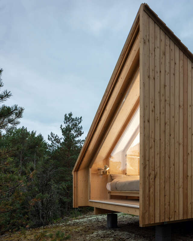Wood structure with lit indoor space as seen from outside.