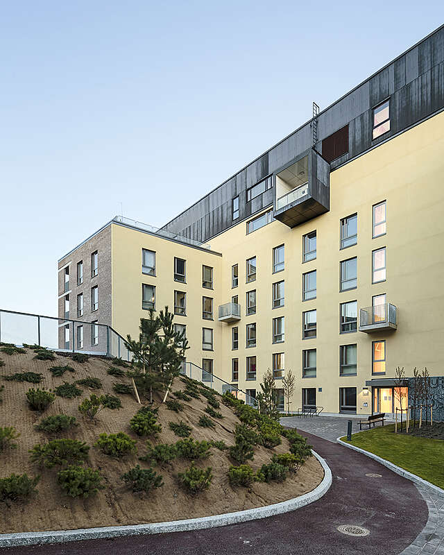 Two toned apartment building with a yellow facade next to the inner courtyard.