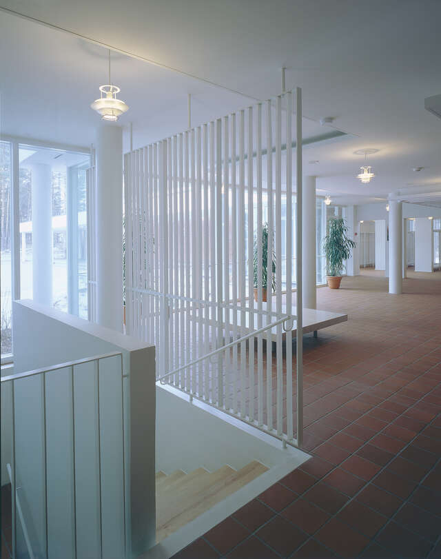 Entrance hall with white surfaces, brown tile floors and wooden stairs leading downstairs.