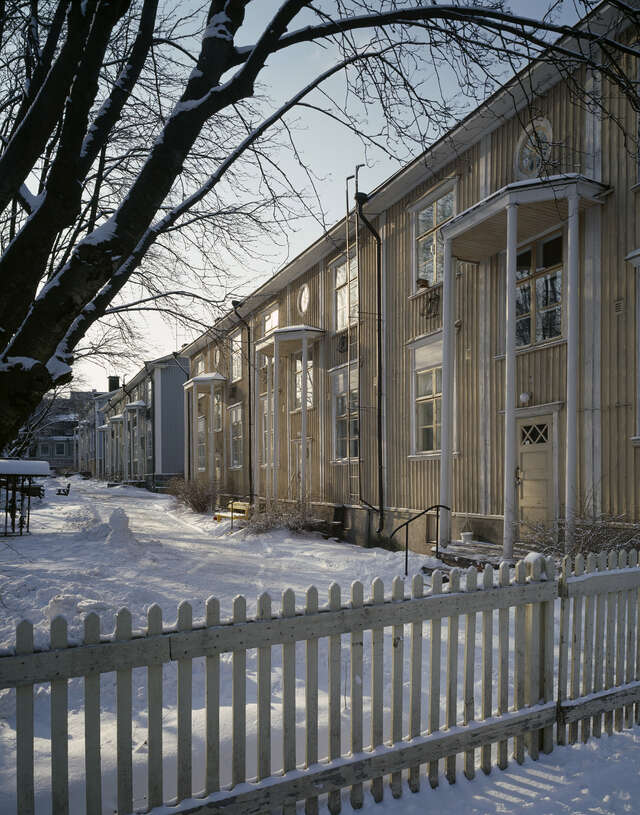 Yellow wooden house with white details on a snowy day.