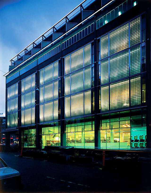 Department store windows at night show an illuminated store.