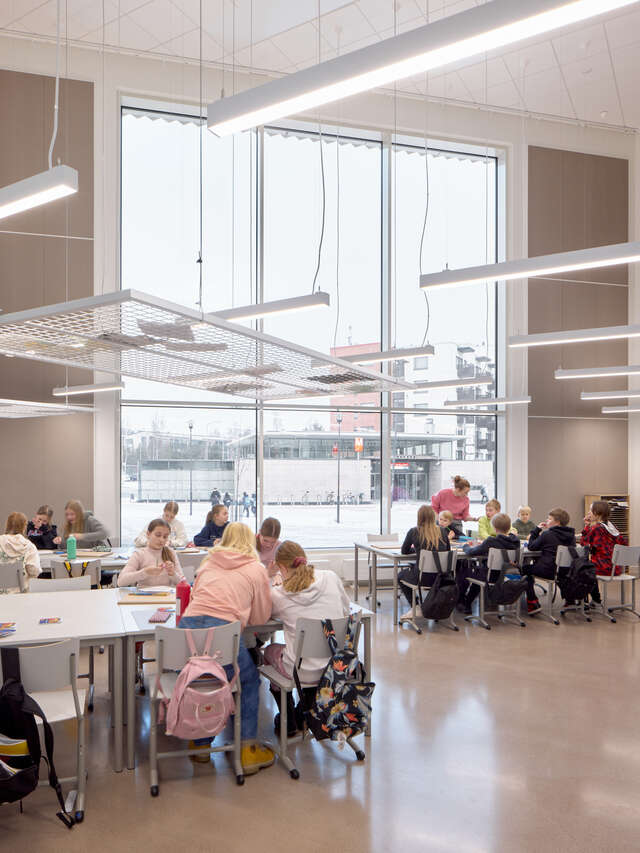 A large indoor space with scattered table groups full of children.