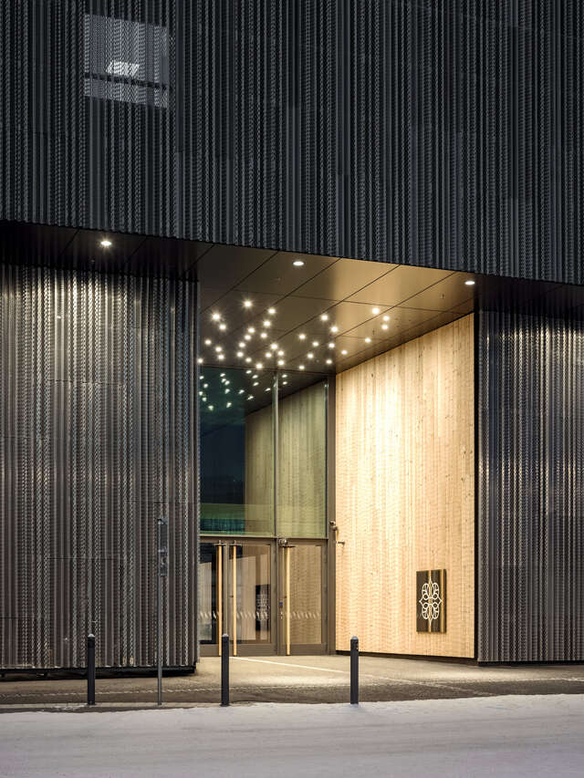 A large black wall of a building with a glass entrance.