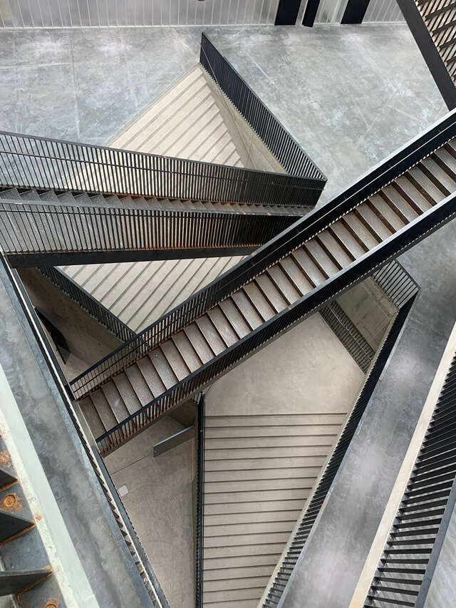 View of multiple narrow staircases going in multiple directions. Image is from above the staircases looking down.