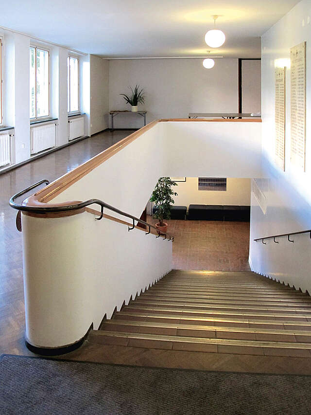White stairway with metal railings and brown tile steps.