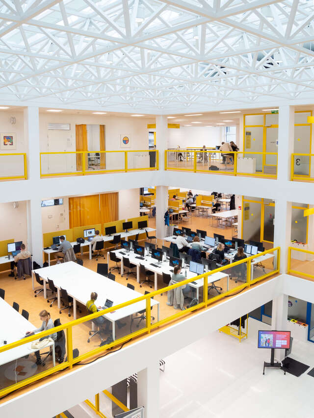 Library lobby area on three levels, white ceiling and walls with bright yellow details.
