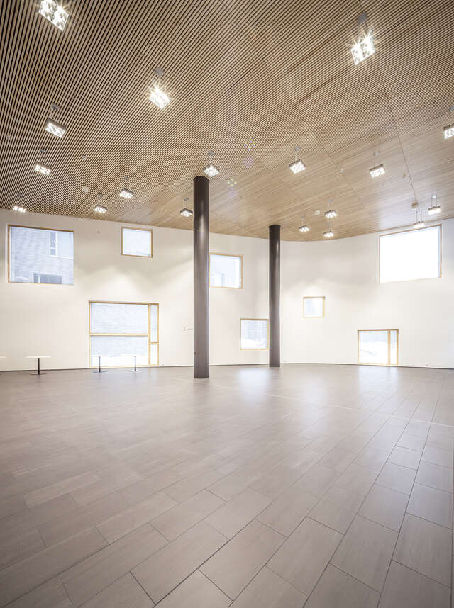 Open space with randomly distributed windows on the walls and two columns in the middle of the room.