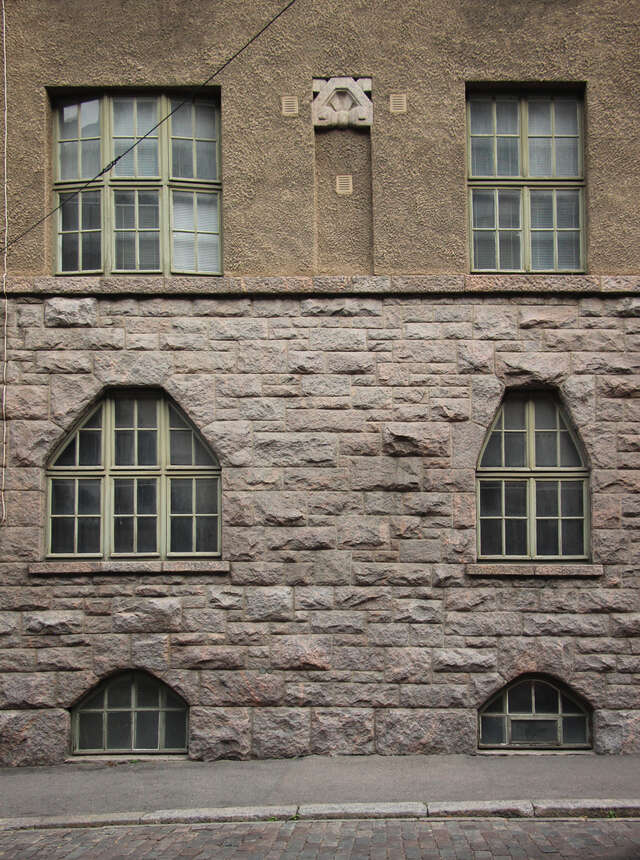 Stone wall at the bottom, beige plaster at the top. The upper two corners of the Botton windows are slanted in.