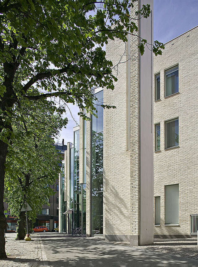 Stepped white brick and glass facade viewed from the street.