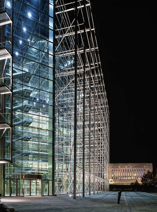 High rise commercial building with a metal grid structure at the front and glass walls.