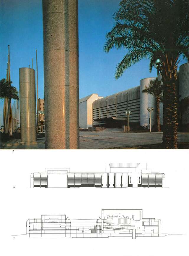 Stone columns and palms in front of a Brutalist congress building.