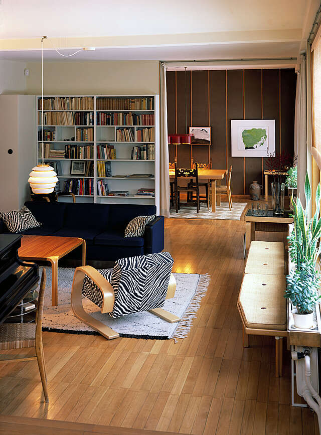 Living room with sitting area and book shelf, and an opening to the dining room in the back