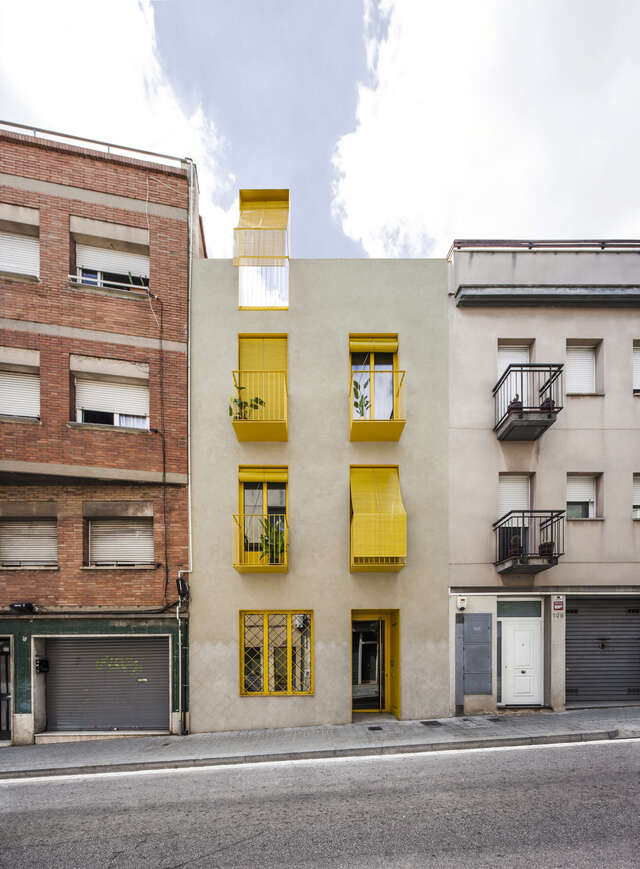 A small apartment building with yellow balconies.