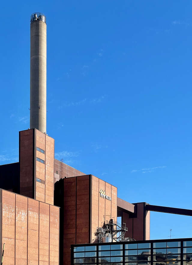 Close-up photo of an industrial building in red brick with a tall chimney