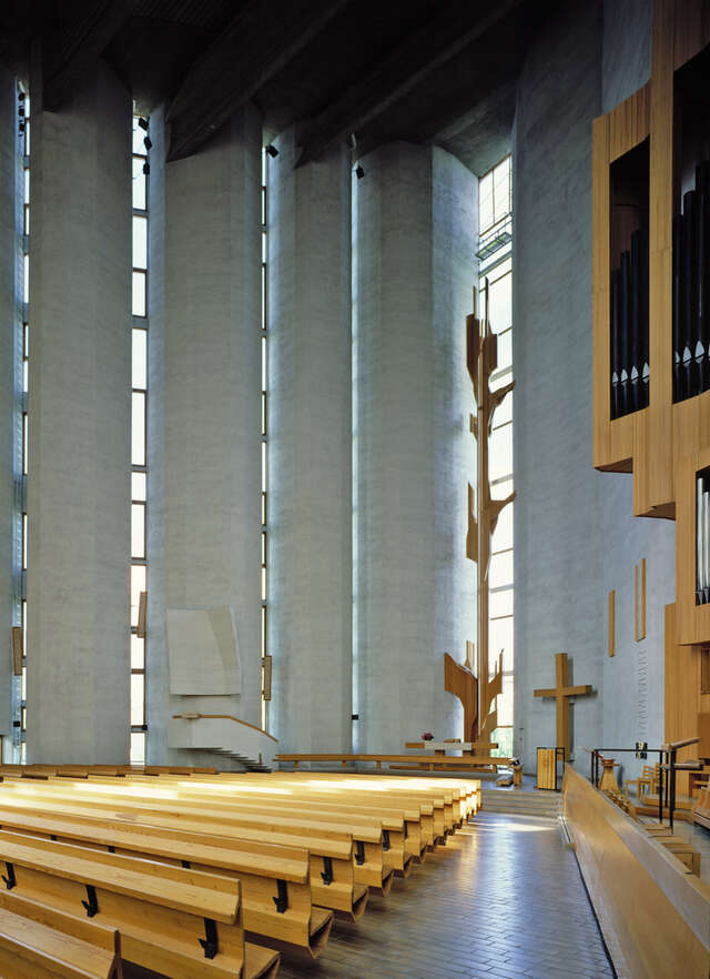 Concrete interior with wooden church furniture .