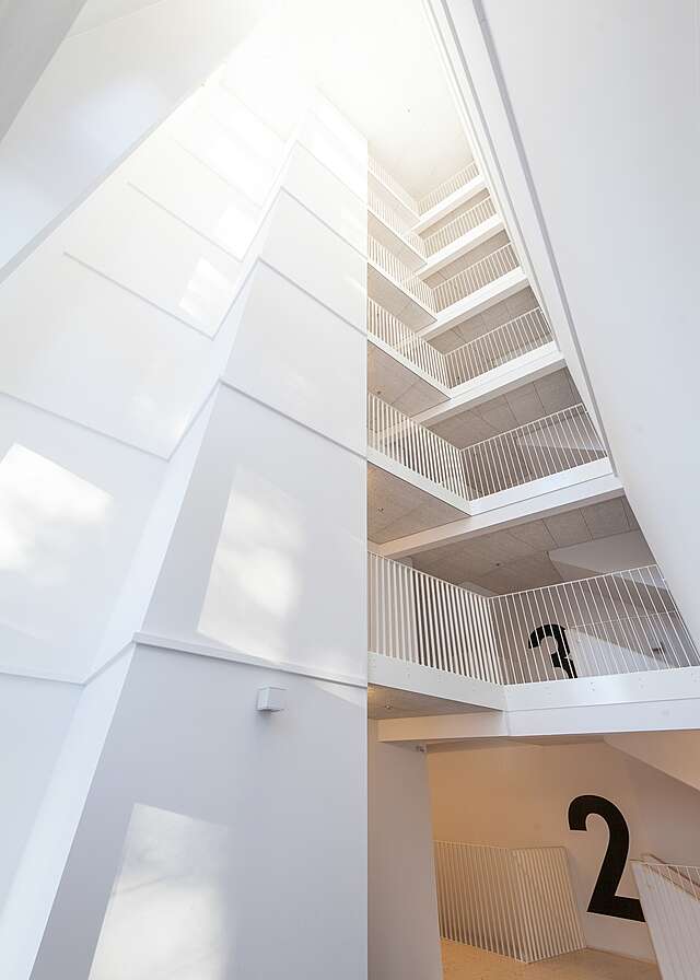 White entrance hall with a view of each level staircase and railing.