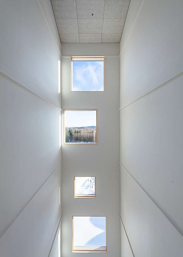 Square windows of different sizes on a tall and narrow wall.