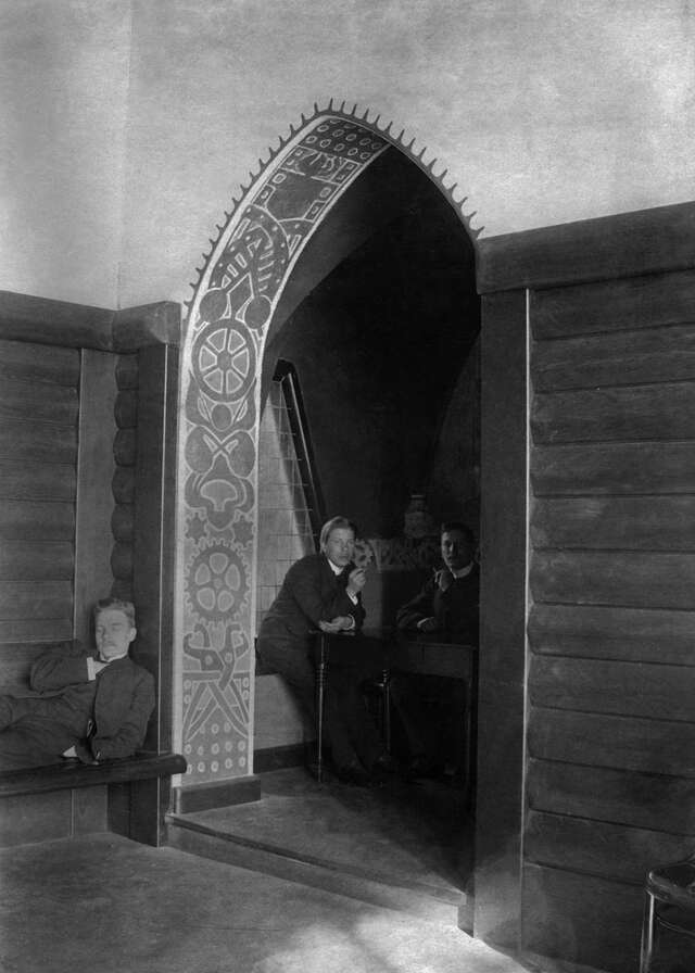 Vanha PoliTwo men sitting in a arched doorway in a black and white picture.
