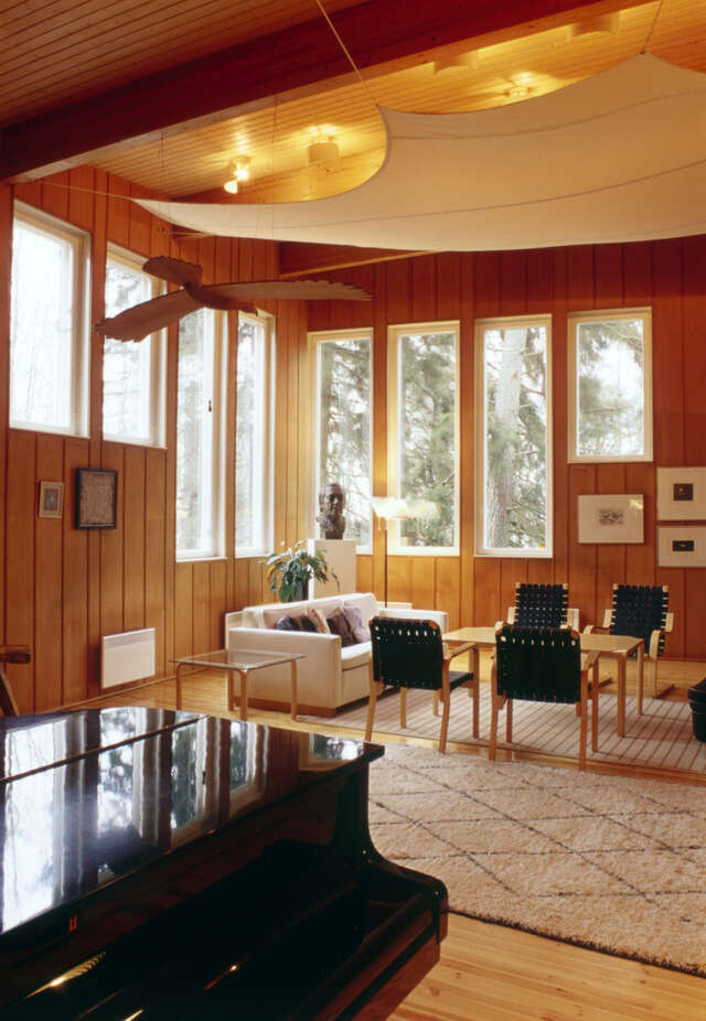 Wooden-paneled walls, sitting area, bellied acoustic ‘sail’ in the ceiling and vertical windows