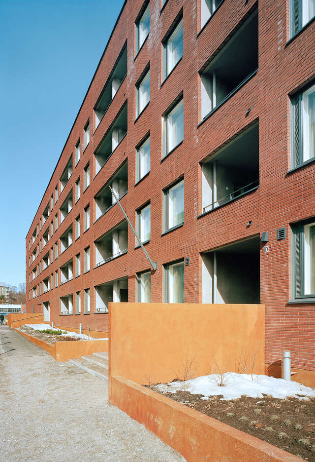 Red brick façade with windows, balconies and narrow front gardens