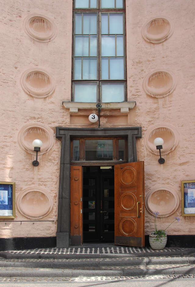 Massive wooden door with a grey frame, surrounded by two rows of medallions on each side of the wall.