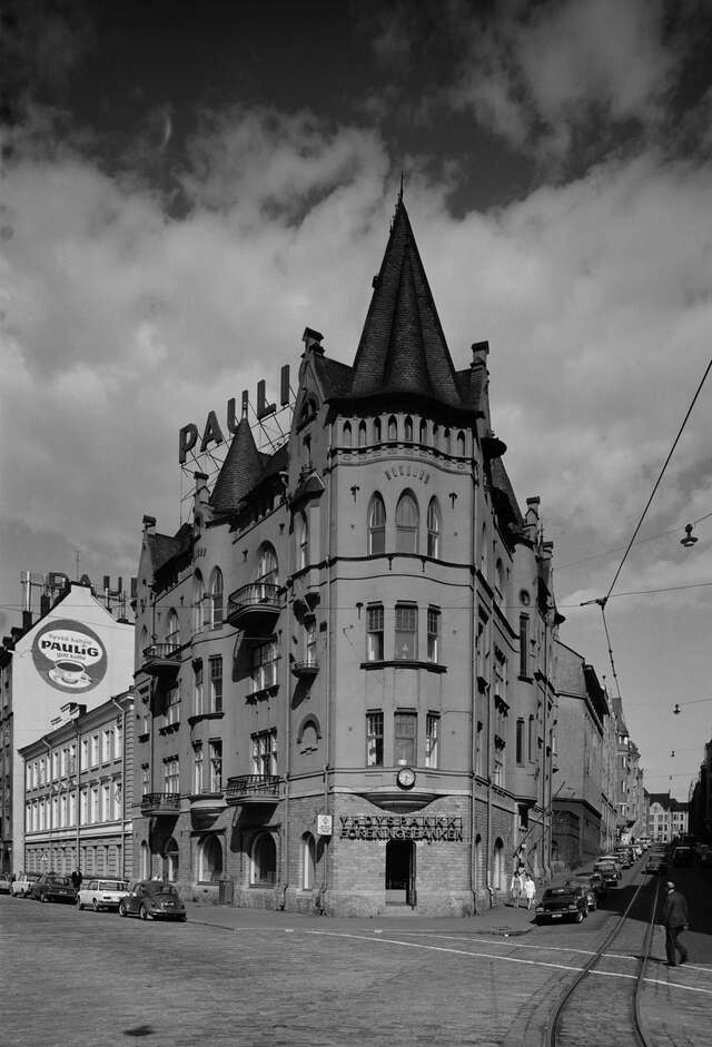 Black and white picture of a brown city house at the corner of a street with a tower at the top.