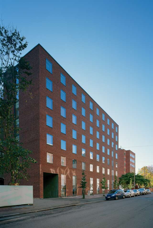 End and façade of a red-brick seven-storey building with square windows