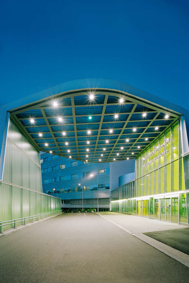 Driveway to the hospital through an illuminated wave-like tunnel